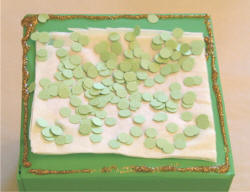Cover the kleenex with confettie or piece of construction paper to hide it.
